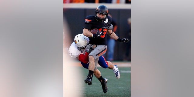 Oklahoma State wide receiver David Glidden (13) is tackled by Kansas defender Ben Heeney (31) in the first quarter of an NCAA college football game in Stillwater, Okla., Saturday, Nov. 9, 2013. (AP Photo/Sue Ogrocki)