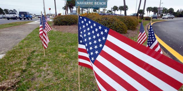 American flags stand in the median near the bridge entrance to Navarre Beach, Fla., Thursday, March 12, 2015. There's been an outpouring of support in this heavily military community following the crash of an Army Black Hawk helicopter Tuesday evening. In various parts of Navarre, 11 flags are placed, one one for each of the servicemen missing in the crash. (AP Photo/Northwest Florida Daily News, Devon Ravine)