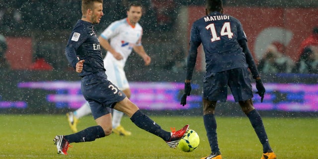 Paris Saint Germain's David Beckham, left, runs with the ball during the League One soccer match between PSG and Marseille at Parc des Princes Stadium, in Paris, Sunday Feb. 24, 2013. Beckham made his Paris St Germain debut as Carlo Ancelotti's men took a potentially vital step towards claiming the Ligue 1 title. (AP Photo/Francois Mori)
