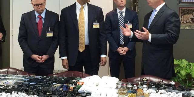 In this photo made available by the South Carolina Department of Corrections on Wednesday, April 6, 2016, their director, Bryan Stirling, right, showing hundreds of cellphones that were seized in a single raid from the Lee Correctional Institution, S.C. Stirling speaks to FCC official Matthew Berry, left, FCC Commissioner Ajit Pai and FCC official Brendan Carr. Stirling wants federal officials to allow the state to block cell signals so contraband phones become useless to inmates. (Stephanie Givens, South Carolina Department of Corrections via AP)