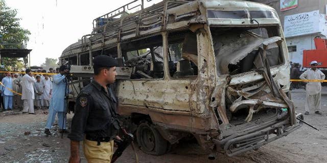 A Pakistani policeman walks past the wreckage of a passenger bus following an explosion in Peshawar, on September 19, 2012