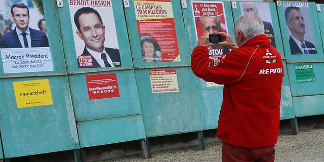 A man takes a picture of electoral posters displaying posters of the presidential candidates in Espelette, southwestern France, Friday, April 14, 2017. The two-round presidential election is set for April 23 and May 7. (AP Photo/Bob Edme)