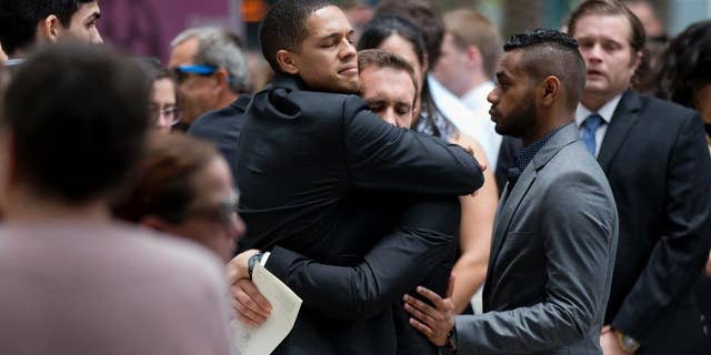 Mourners embrace after the funeral service for Christopher Leinonen.