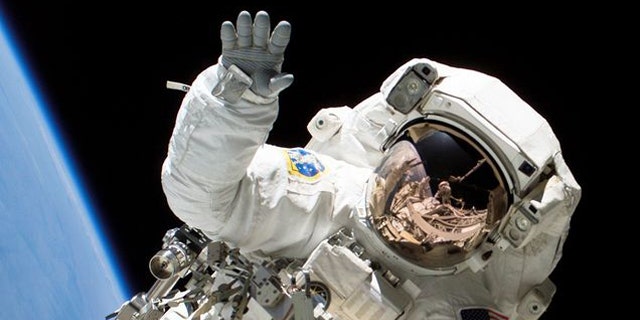 Astronaut Heidemarie M. Stefanyshyn-Piper waves at the camera during a spacewalk.