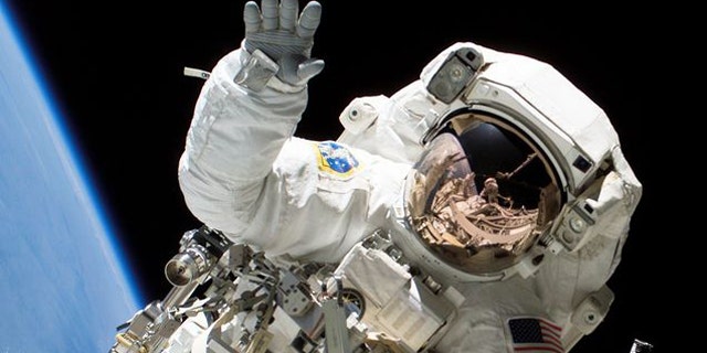 Astronaut Heidemarie M. Stefanyshyn-Piper waves at the camera during a spacewalk.