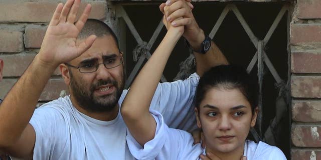 FILE - In this Thursday, Aug. 28, 2014 file photo prominent Egyptian blogger Alaa Abdel-Fattah, left, with his sister Sanaa Abdel-Fattah , speaks to the crowd after attending their father's funeral in Cairo, Egypt. Officials said the prominent activist voluntarily gave herself up to police on Saturday to start a six-month sentence passed against her last week for insulting the judiciary. (AP Photo/Hassan Ammar, File)