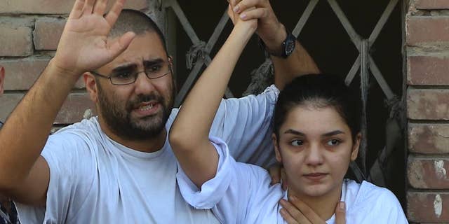 FILE - In this Thursday, Aug. 28, 2014 file photo prominent Egyptian blogger Alaa Abdel-Fattah, left, with his sister Sanaa Abdel-Fattah , speaks to the crowd after attending their father's funeral in Cairo, Egypt. Officials said the prominent activist voluntarily gave herself up to police on Saturday to start a six-month sentence passed against her last week for insulting the judiciary. (AP Photo/Hassan Ammar, File)