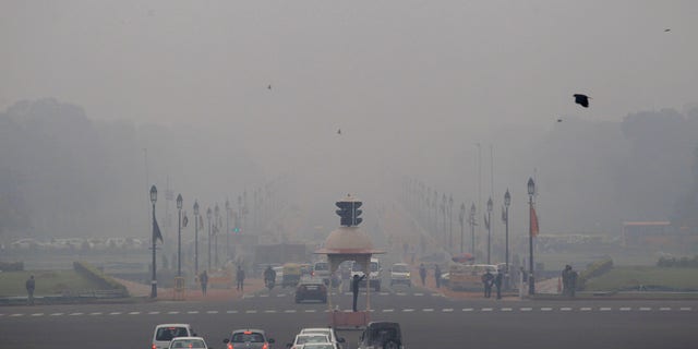 Smog and fog envelop the Rajpath, the ceremonial boulevard, behind, as a police man, center, controls traffic in the morning in New Delhi, India, Wednesday, Feb. 5, 2014. On bad days in India’s congested capital, the air is so murky it slows traffic to a crawl because visibility is so poor. Conversations are punctuated with rasping coughs. Weak bands of sunlight filter through a grainy sky. (AP Photo/Tsering Topgyal)