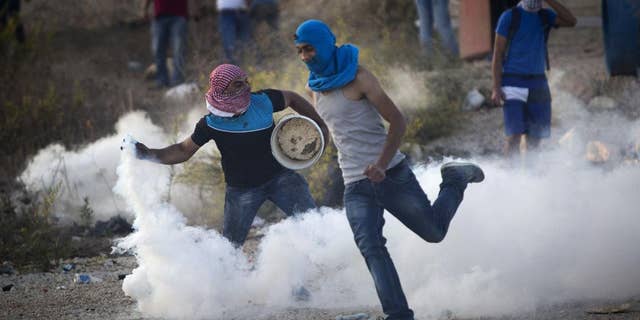 A Palestinian protester throws back a tear gas canister that was fired by Israeli troops during clashes near Ramallah, West Bank, Thursday, Oct. 15, 2015. In the current wave of violence, eight Israelis have been killed in stabbing and shooting attacks, as of Thursday. Thirty-one Palestinians have been killed, including 14 identified by Israel as attackers, and the others in clashes between stone-throwers and Israeli troops. (AP Photo/Majdi Mohammed)