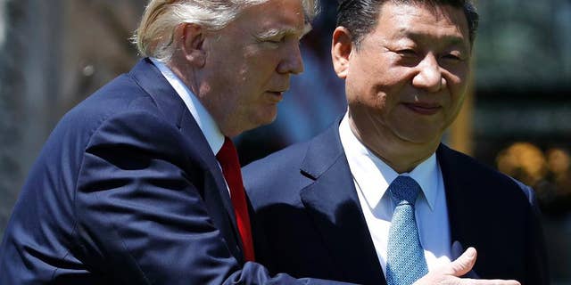 In this April 7, 2017, file photo, U.S. President Donald Trump gestures as he and Chinese President Xi Jinping walk together after their meetings at Mar-a-Lago in Palm Beach, Fla.