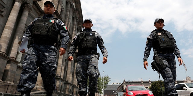 FILE: Police officers walk on the main square a day after local election in Toluca, Mexico.