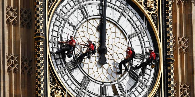 FILE- In this file photo dated Monday, Aug. 18, 2014, workers abseil outside the clock face as they clean Big Ben's clock tower of the Houses of Parliament in London. According to reports published Sunday Oct. 18, 2015, the chimes of Big Ben may fall silent for many months as urgent repairs are carried out to the clock and the tower, which must begin as soon as possible.(AP Photo/Sang Tan, FILE)