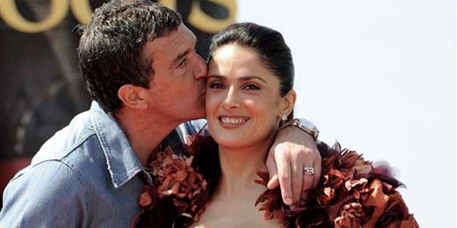 Actor Antonio Banderas, left, kisses actress Salma Hayek on the cheek during a photo call for Puss in Boots, at the 64th international film festival, in Cannes, southern France, Wednesday, May 11, 2011. (AP Photo/Jonathan Short)