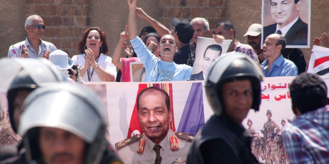 Egyptian pro-Mubarak supporters flash his posters and a giant poster showing field Marshal Mohammed Hussein Tantawi, at center, outside police academy court in Cairo, Egypt, Sunday, Sept.11, 2011 where Mubarak, his two sons Alaa and Gamal, his security chief Habib el-Adly and six top police officers face a session of trial, on charges they ordered the use of lethal force against protesters during Egypt's 18-day uprising killing 850 protesters were killed. Tantawi, Egypt's military ruler Tantawi and one-time confidant of Hosni Mubarak, has failed to attend a court session in which he was expected to offer highly anticipated testimony about the former president's alleged role in the death of protesters.