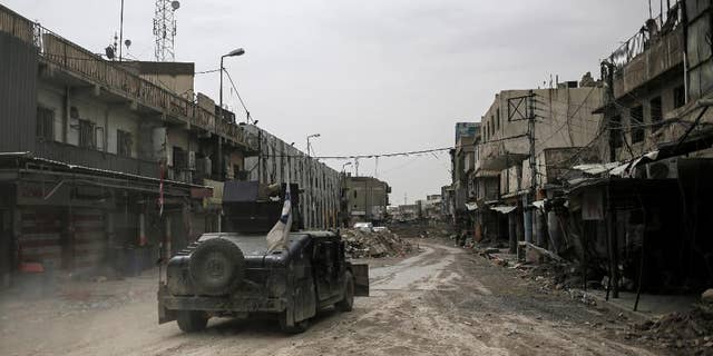 In this Tuesday, May 2, 2017 photo, a humvee of the Iraqi Federal Police drives through an abandoned street in western Mosul, Iraq. The spokesman for the ministry of defense said Thursday, May 4, 2017, that Iraqi forces have begun a push along the northern edge of Mosul's western half where Islamic State group fighters are holding onto a cluster of neighborhoods. The front lines in western Mosul have inched forward for months as IS fighters have used a claustrophobic battle space and hundreds of thousands of civilians as human shields to slow Iraqi troops. (AP Photo/Bram Janssen)