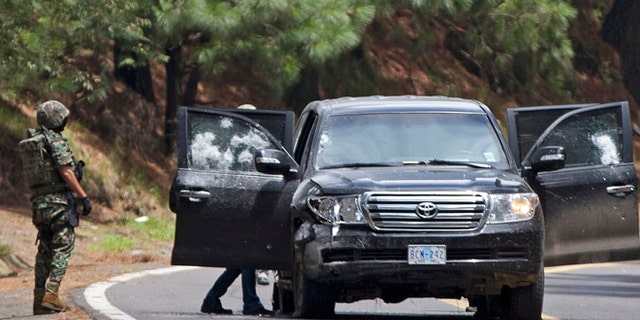 An armored U.S. Embassy vehicle is checked by military personal after it was attacked near Tres Marias, Mexico, in August. (AP)