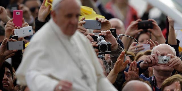 Faithful take pictures of Pope Francis touring St.Peter's Square aboard of his pope-mobile as he arrives for his general audience at the Vatican, Wednesday, April 9, 2014. (AP Photo/Gregorio Borgia)