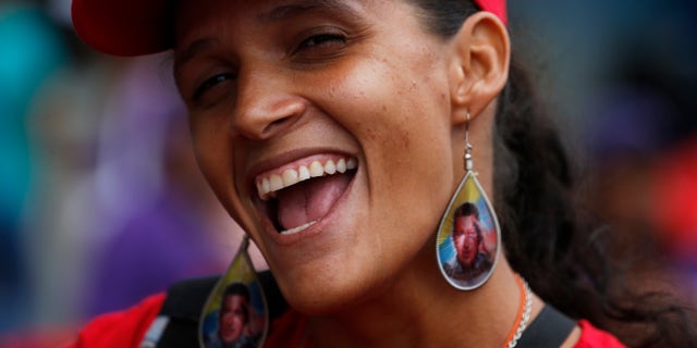 A woman wearing earrings designed with an image of the late President Hugo Chavez, smiles during a pro-government rally in Caracas, Venezuela, Saturday, Feb. 22, 2014. Venezuelans on both sides of the nation's political divide took to the streets on Saturday after nearly two weeks of mass protests that have Venezuelan President Nicolas Maduro scrambling to reassert his leadership. (AP Photo/Fernando Llano)
