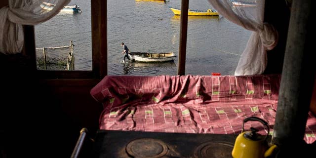 In this May 10, 2016, Marco, the 19-year-old son of fisherwoman Marisol Millaquien prepares to take out a boat on an expedition, in hopes of providing food for the dinner table, in Quetalmahue, on Chile's Chiloe Island, during the country's worst ever "red tide" environmental disaster. The view from Millaquien's stilt home is desolate: dozens of abandoned ghostly boats, dead birds and shellfish. "I'm 46. I've seen red tide before, but never like this," she said. (AP Photo/Esteban Felix)