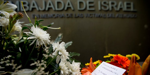A piece of paper reading in Spanish "Relatives and survivors, March 17, 2015, March 17, 1992" is placed on floral arrangements that sit where the Israeli Embassy used to be, during an act to commemorate the 23rd anniversary of the bomb attack that destroyed the Israeli Embassy building killing 22 people in Buenos Aires, Argentina, Tuesday, March 17, 2015. (AP Photo/Natacha Pisarenko)