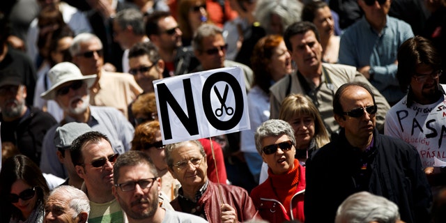 A protestor walks holding a banner reading 'No' during a demonstration against regional government imposed austerity plans to restructure and part privatize the health care sector in Madrid, Sunday, April 21, 2013. Madrid proposes selling off the management of six of 20 public hospitals and 27 of 268 health centers. Spain's regions are struggling with a combined debt of $190 billion (145 billion euro) as the country's economy contracts into a double-dip recession triggered by a 2008 real estate crash. (AP Photo/Daniel Ochoa de Olza)