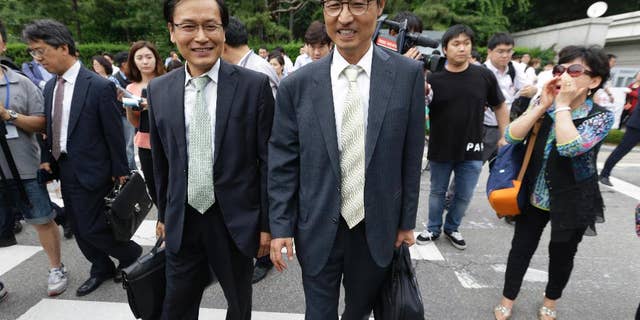 South Korean human right lawyers leave after a court hearing on the detention of North Korean defectors as an anti-North Korean protester, right, shouts to them in front of the Seoul District Court in Seoul, South Korea, Tuesday, June 21, 2016. As South Korea's main spy agency prepares a courtroom defense of its continued detention of 12 North Korean waitresses it says fled from China, Pyongyang is using the women's relatives and colleagues to step up its accusations that they were tricked into leaving their jobs and essentially kidnapped.(AP Photo/Ahn Young-joon)
