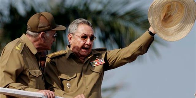 ALTERNATIVE CROP OF HAV121 - Cuba's President Raul Castro waves his hat during a military parade to commemorate the 50th anniversary of the Bay of Pigs failed invasion in Havana, Cuba, Saturday April 16, 2011. Cuba kicked off a crucial Communist Party congress Saturday with the parade to mark 50 years since the defeat of CIA-backed exiles at the Bay of Pigs. At left is Vice President of the Council of State of Cuba and the Cuban Minister of the Interior Abelardo Colomé. (AP Photo/Javier Galeano)