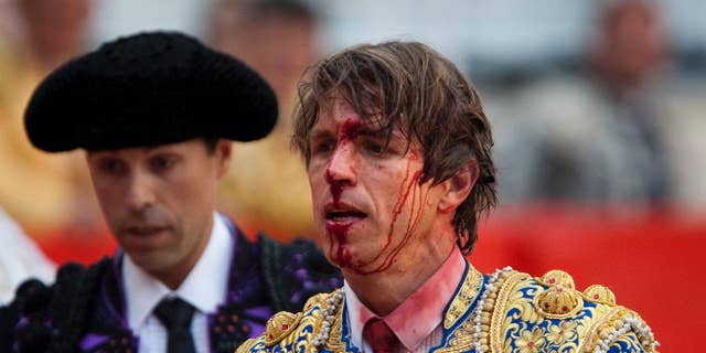 FILE - In this April 25, 2010 file photo, bullfighter Manuel Diaz "El Cordobes", right, reacts after being gored by a bull during a bullfight at the Monumental Bullring in Barcelona, Spain. The southern Cordoba city court has held a hearing into a decades-old paternity dispute over whether two of Spain's most well-known bullfighters and who share the same showname, 'El Cordobes', are really father and son. The court began studying the claim Thursday April 28, 2016 by Manuel Diaz, 47 that he is the son of retired bullfighting legend Manuel Benitez, 79, something the elder torero has never recognized. (AP Photo/Emilio Morenatti, File)