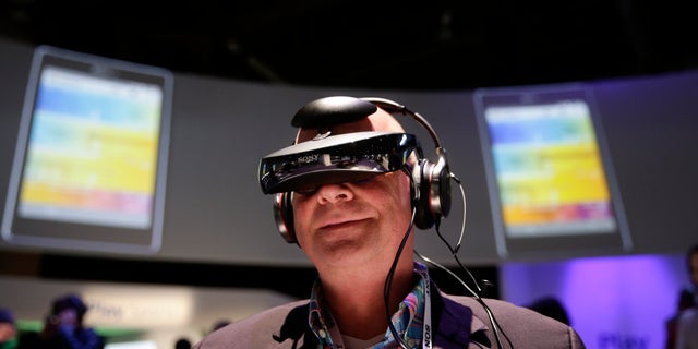 Juergen Boyny, of Germany, watches a video clip with a personal viewing device at the Sony booth at the International Consumer Electronics Show(CES) on Thursday, Jan. 9, 2014, in Las Vegas. (AP Photo/Jae C. Hong)