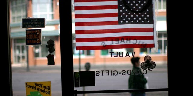 HAZLETON, PA - MARCH 14:  A woman walks pass an American flag in a store window March 14, 2007 in Hazleton, Pennsylvania. A new city ordinance in Hazleton has caused members of the large Latino community to fear discrimination and have concern for their future in the town. The city of Hazleton and its aggressive policy on illegal immigration is the subject of a federal trial that is being viewed nationally as a landmark case on immigration. In a move that caused outrage among Latino residents this past summer, city officials in Hazleton adopted ordinances that target illegal immigrants in housing, language use and employment. The ordinance, called the Illegal immigration Relief Act, has been put on hold while the case is challenged in federal court in Scranton by the American Civil Liberties Union and the Puerto Rican Legal Defense and Education Fund. At least 80 towns and cities across the nation have adopted similar measures against illegal immigrants.  (Photo by Spencer Platt/Getty Images)