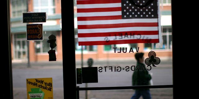 HAZLETON, PA - MARCH 14: A woman walks pass an American flag in a store window March 14, 2007 in Hazleton, Pennsylvania. A new city ordinance in Hazleton has caused members of the large Latino community to fear discrimination and have concern for their future in the town. The city of Hazleton and its aggressive policy on illegal immigration is the subject of a federal trial that is being viewed nationally as a landmark case on immigration. In a move that caused outrage among Latino residents this past summer, city officials in Hazleton adopted ordinances that target illegal immigrants in housing, language use and employment. The ordinance, called the Illegal immigration Relief Act, has been put on hold while the case is challenged in federal court in Scranton by the American Civil Liberties Union and the Puerto Rican Legal Defense and Education Fund. At least 80 towns and cities across the nation have adopted similar measures against illegal immigrants. (Photo by Spencer Platt/Getty Images)