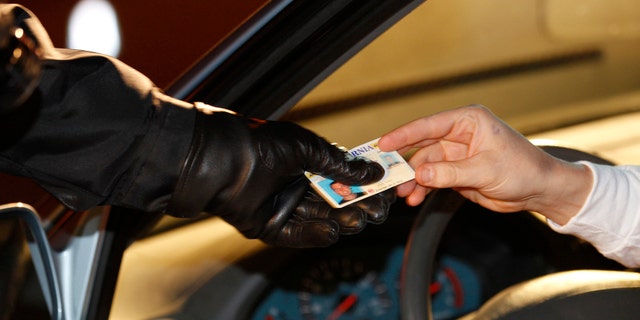In this Dec. 16, 2011 photo a police officer checks a driver's license at a sobriety check point in Escondido, Calif.