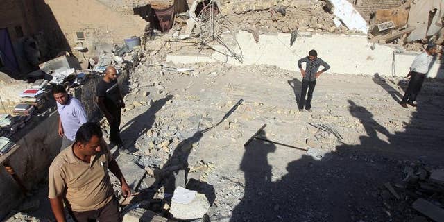 Iraqis inspect the scene following an explosion at the Al-Hussein mosque south of Baghdad, on September 30, 2013