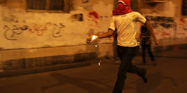 A Bahraini anti-government protester prepares to throw a petrol bomb at riot police during clashes following a rally protesting against the upcoming Formula One race in Sanabis, Bahrain, Tuesday, April 9, 2013. The Bahrain Grand Prix is to be held April 21. Bahrain says four suspects have been arrested after homemade firebombs were hurled at the foreign ministry in a possible escalation of anti-government protests. (AP Photo/Hasan Jamali)