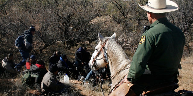 A U.S. Border Patrol agent watches over a group of immigrants arrested after crossing illegally from Mexico through the Altar Valley in Arizona. (File photo)