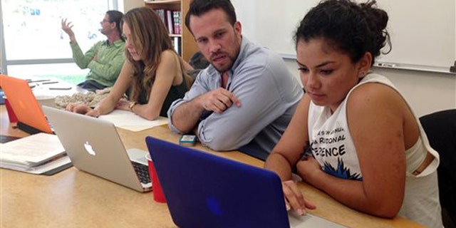 CORRECTS NAMES AND AGES Anthony Rouzier helps Valentina Adarraga, 20, sign up for health insurance under the Affordable Care Act in Miami, Friday, March 21, 2014. Rouzier took five hours of training to be become a certified application counselor to assist those that want to enroll in the federal health care program.
