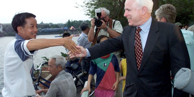 Vietnam war veteran and Sen. John McCain shakes hands with a Vietnamese man on the banks of Truc Bach lake, where former Navy pilot McCain was shot down in 1967 during the Vietnam War.