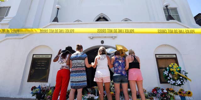 June 18, 2015: A group of women pray together at a makeshift memorial on the sidewalk in front of the Emanuel AME Church in Charleston, S.C.