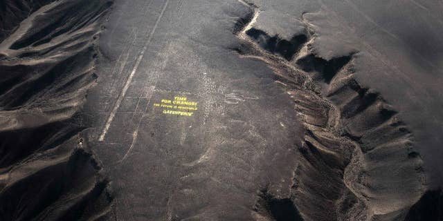 Greenpeace activists stand next to massive letters delivering the message "Time for Change: The Future is Renewable," next to the hummingbird geoglyph in Nazca in Peru, Monday, Dec. 8, 2014. Greenpeace activists from Brazil, Argentina, Chile, Spain, Germany, Italy and Austria displayed the message, which can be viewed from the sky, during the climate talks in Peru, to honor the Nazca people, whose ancient geoglyphs are one of the country's cultural landmarks. (AP Photo/Rodrigo Abd)