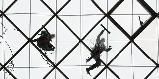 Two window cleaners work on the 27-meters-high glass ceiling of a building in Dresden, Germany, Wednesday, March 30, 2016. (Sebastian Kahnert/dpa via AP)