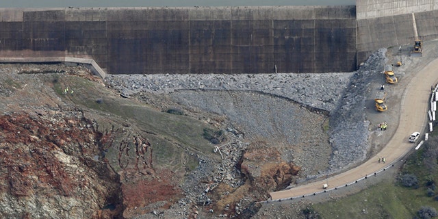 Erosion caused when overflow water cascaded down the emergency spillway, right, of the Oroville Dam in California.