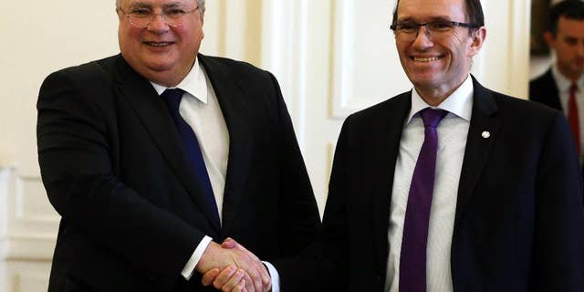 Greek Minister for Foreign Affairs Nikos Kotzias, left, shakes hands with the U.N. Special Advisor of the Secretary-General Espen Barth Eide before their meeting to discuss the progress of Cyprus Peace Talks in Athens, Friday, Feb. 3, 2017. The rival leaders of ethnically split Cyprus have asked the United Nations to prepare for a follow-up summit in early March that will aim to clinch a breakthrough on the difficult issue of how security will be handled after the island is reunified, a U.N. envoy said Wednesday. (AP Photo/Thanassis Stavrakis)