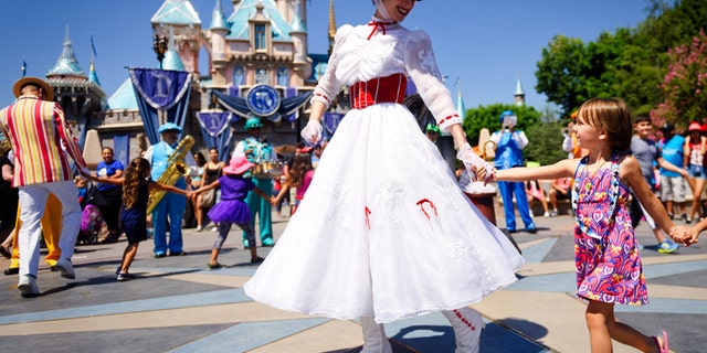 Anaheim, CA - August 10th 2016: Mary Poppins smiles at a young child as she leads a line of children in song and dance in front of Cinderella's castle during Disney's 60th Diamond Celebration.
