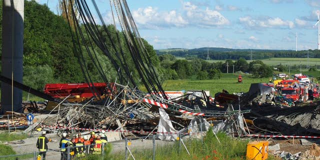 Firefighters stand near a collapsed scaffolding at a highway bridge near Werneck northern Bavaria, Germany Wednesday June 15, 2016. German news agency dpa is reporting that the scaffolding has collapsed on a highway bridge that was under construction in southern Germany. ( Nicolas Armer/dpa via AP)