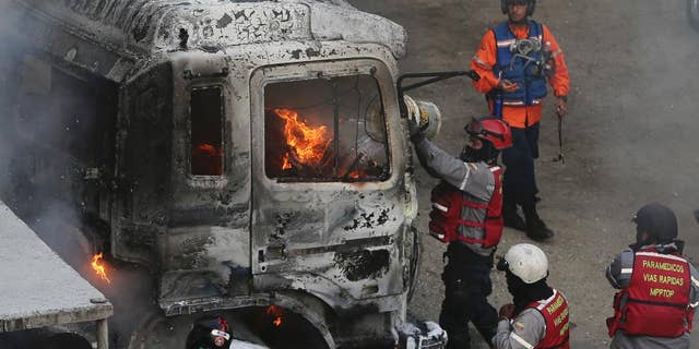 Fire-fighters put out a truck set on fire during anti-government protests in Caracas, Venezuela, Monday, April 24, 2017. Thousands of protesters shut down the capital city's main highway to express their disgust with the socialist administration of President Nicolas Maduro. Protesters in least a dozen other cities also staged sit-ins as the protest movement is entering its fourth week. (AP Photo/Fernando Llano)