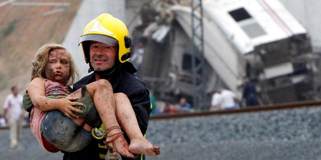 A fireman carries a wounded victim from the wreckage of a train crash near Santiago de Compostela, northwestern Spain.