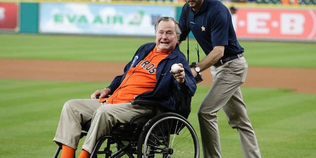 FILE - In this April 12, 2016 file photo, former President George H.W. Bush, left, shows his pitching grip as he wheeled out to the field to throw out the ceremonial first pitch to Houston Astros starting pitcher Collin McHugh before the baseball game against the Kansas City Royals in Houston. Fresh from his 92nd birthday, former President George H.W. Bush is enjoying himself in Maine after recovering from a fall at his home nearly a year ago. Bush led a group of 40 wounded warriors on a fishing trip at the helm of his speedboat Wednesday, June 15, 2016, three days after a low-key birthday celebration. (AP Photo/Pat Sullivan, File)