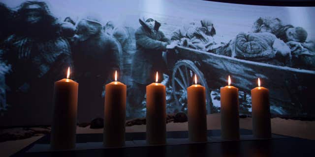 Memorial candles are lit in front of a photo taken during WWII showing refugees fleeing from the Nazis at a ceremony marking International Holocaust Remembrance Day in Russia’s first Jewish Museum in Moscow, Russia, Sunday, Jan. 27, 2013. (AP Photo/Alexander Zemlianichenko Jr)