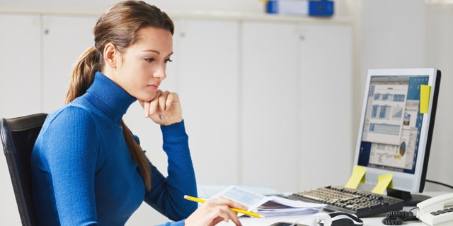 portrait of business woman typing on calculator