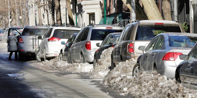Some snow-bound cars line one side of a street in New York's Upper West Side neighborhood, Wednesday, Feb. 25, 2015. For the first time in weeks, New York City's alternate side parking rules are back in place after being suspended to allow for snow removal. (AP Photo/Richard Drew)